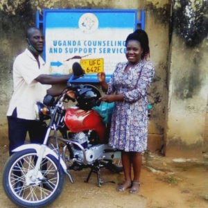 A UCSS Teacher stands happily with her new motorbike, donated by a UCSS partner this month! 